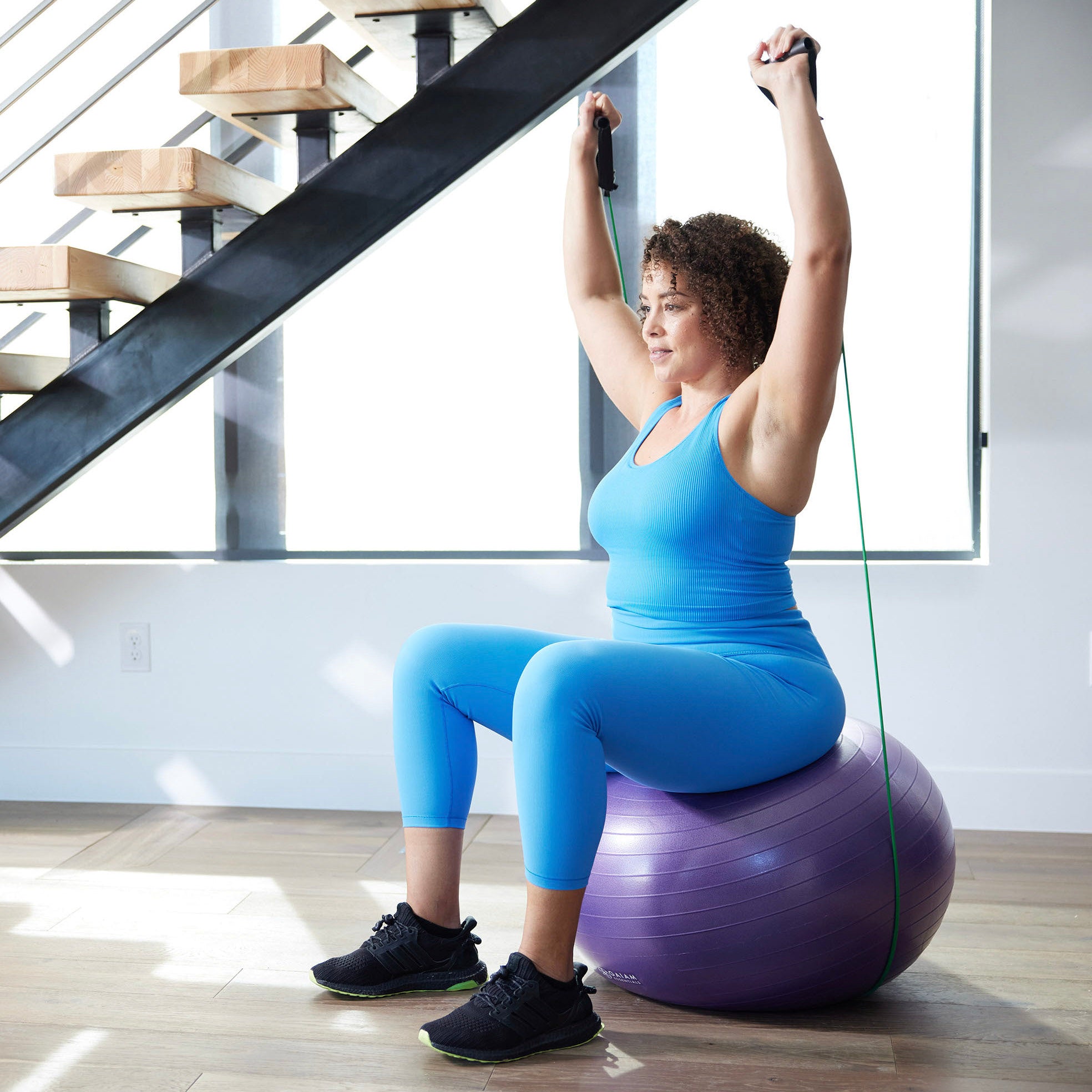 Woman using resistance bands on balance ball